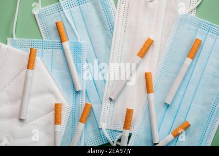 Masques chirurgicaux protecteurs avec des cigarettes sur fond vert.épidémie de coronavirus concept Banque D'Images