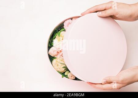 Gros plan les mains des femmes ouvrant les boîtes-cadeaux avec des fleurs fraîches. Le printemps arrive, journée internationale des femmes, bonne Saint Valentin, 8 mars, fête des mères Banque D'Images