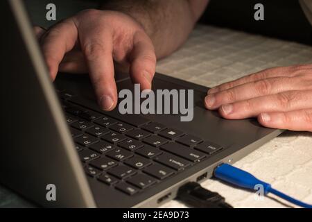 Saisie des doigts sur le clavier d'un ordinateur portable.apprentissage des élèves masculins à la maison Banque D'Images