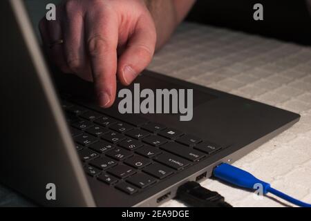 Appuyez d'un seul doigt sur le clavier de l'ordinateur portable.main sur le clavier de l'ordinateur portable.Homme travaillant au bureau à domicile.vue rapprochée. Banque D'Images