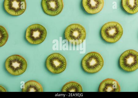 Les motifs des tranches de kiwi sur fond vert comme fond continu. Fond de fruit conceptuel texturé Banque D'Images
