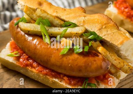 Sandwich à la saucisse merguez frites maison avec Harrisa on a Bun Banque D'Images