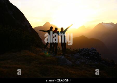 3 jeunes femmes en formation au coucher du soleil en direction d'Arnspitzen, dans les montagnes Wetterstein, ont pris sur le Gamseck au-dessus de la cabane Mittenwalder Banque D'Images