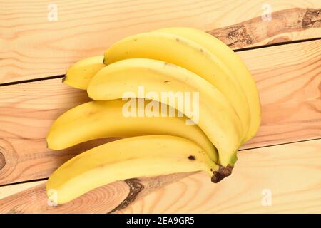 Plusieurs bananes biologiques juteuses mûres jaunes et brillantes sur une table en bois naturel. Banque D'Images
