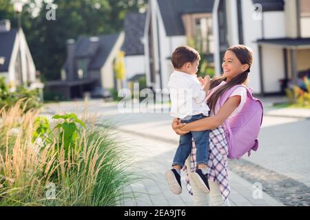 Photo portrait d'une écolière souriante et gaie tenant son petit frère plein air dans la rue en été Banque D'Images