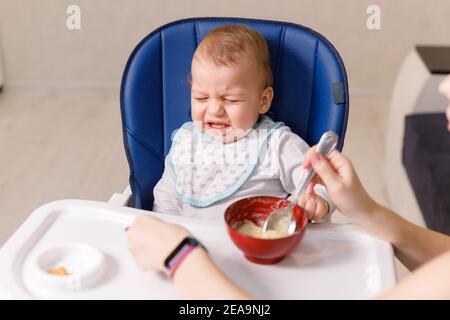 La mère essaie de se nourrir avec une cuillère Naughty bébé enfant refusant manger Banque D'Images