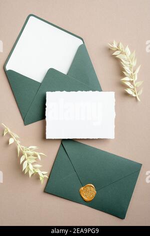 Carte de mariage et enveloppes vertes sur fond beige pastel. Flat lay, vue de dessus, espace de copie. Banque D'Images