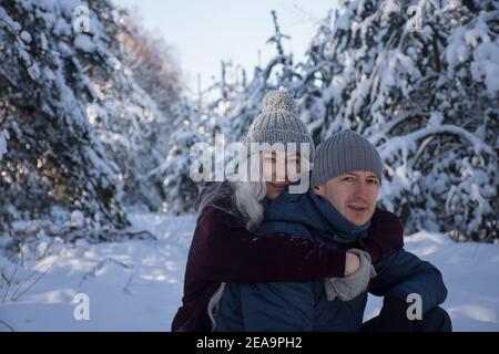 un couple heureux qui se promède dans la forêt enneigée Banque D'Images