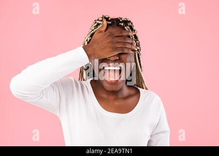 Bonne jeune femme afro-américaine couvrant ses yeux avec la main Banque D'Images