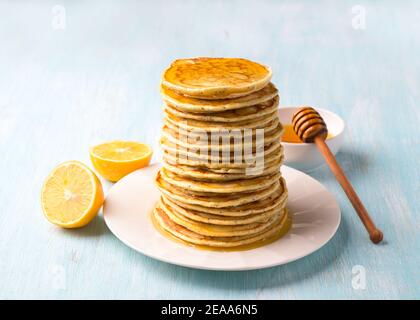 Crêpes au citron avec graines de pavot et miel sur fond bleu. Délicieux plats faits maison Banque D'Images