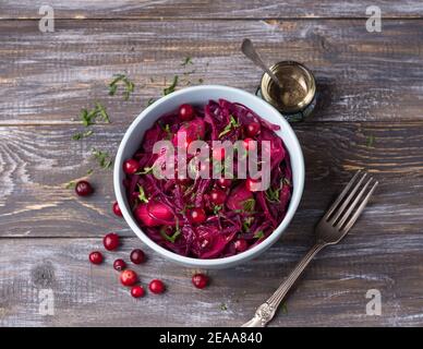 Sauce au chou rouge avec pommes, canneberges, épices et légumes verts sur fond de bois. Délicieux aliments sains faits maison Banque D'Images