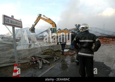 Les pompiers travaillent dans les ruines d'un entrepôt textile chinois qui a été incendié la 12e nuit des émeutes dans la banlieue parisienne du Bourget, en France, le 5 novembre 2005. De petits groupes mobiles de jeunes ont incendié des centaines de voitures supplémentaires et les violences et les attaques incendiaires qui ont secoué la banlieue de la capitale pendant une semaine se sont répandues dans d'autres villes françaises. Photo de Mehdi Taamallah/ABACAPRESS.COM Banque D'Images