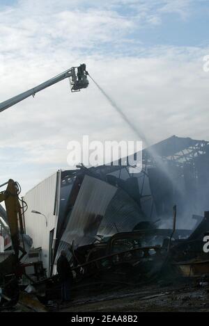 Les pompiers travaillent dans les ruines d'un entrepôt textile chinois qui a été incendié la 12e nuit des émeutes dans la banlieue parisienne du Bourget, en France, le 5 novembre 2005. De petits groupes mobiles de jeunes ont incendié des centaines de voitures supplémentaires et les violences et les attaques incendiaires qui ont secoué la banlieue de la capitale pendant une semaine se sont répandues dans d'autres villes françaises. Photo de Mehdi Taamallah/ABACAPRESS.COM Banque D'Images