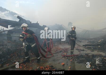 Les pompiers travaillent dans les ruines d'un entrepôt textile chinois qui a été incendié la 12e nuit des émeutes dans la banlieue parisienne du Bourget, en France, le 5 novembre 2005. De petits groupes mobiles de jeunes ont incendié des centaines de voitures supplémentaires et les violences et les attaques incendiaires qui ont secoué la banlieue de la capitale pendant une semaine se sont répandues dans d'autres villes françaises. Photo de Mehdi Taamallah/ABACAPRESS.COM Banque D'Images