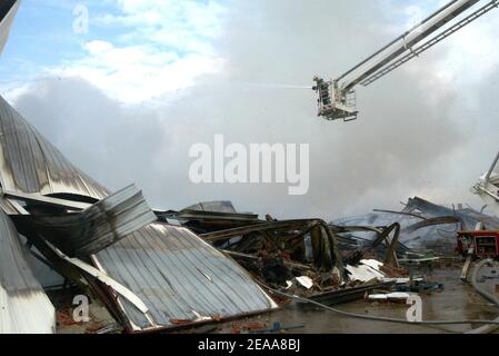 Les pompiers travaillent dans les ruines d'un entrepôt textile chinois qui a été incendié la 12e nuit des émeutes dans la banlieue parisienne du Bourget, en France, le 5 novembre 2005. De petits groupes mobiles de jeunes ont incendié des centaines de voitures supplémentaires et les violences et les attaques incendiaires qui ont secoué la banlieue de la capitale pendant une semaine se sont répandues dans d'autres villes françaises. Photo de Mehdi Taamallah/ABACAPRESS.COM Banque D'Images