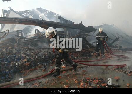 Les pompiers travaillent dans les ruines d'un entrepôt textile chinois qui a été incendié la 12e nuit des émeutes dans la banlieue parisienne du Bourget, en France, le 5 novembre 2005. De petits groupes mobiles de jeunes ont incendié des centaines de voitures supplémentaires et les violences et les attaques incendiaires qui ont secoué la banlieue de la capitale pendant une semaine se sont répandues dans d'autres villes françaises. Photo de Mehdi Taamallah/ABACAPRESS.COM Banque D'Images