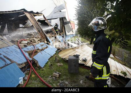 Les pompiers travaillent dans les ruines d'un entrepôt textile chinois qui a été incendié la 12e nuit des émeutes dans la banlieue parisienne du Bourget, en France, le 5 novembre 2005. De petits groupes mobiles de jeunes ont incendié des centaines de voitures supplémentaires et les violences et les attaques incendiaires qui ont secoué la banlieue de la capitale pendant une semaine se sont répandues dans d'autres villes françaises. Photo de Mehdi Taamallah/ABACAPRESS.COM Banque D'Images