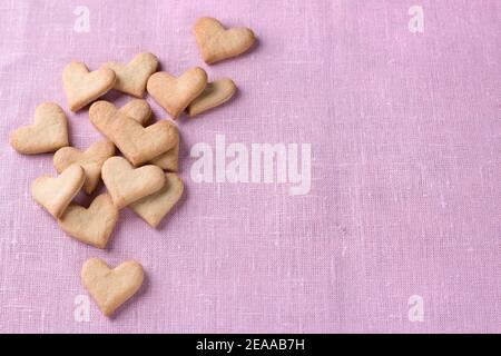 Biscuits cœurs pour la Saint-Valentin sur fond textile rose, vue de dessus, espace libre Banque D'Images