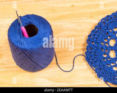 Morceau en crochet en laine et tricoté à la main, détail bouton en laine bleue avec crochet en crochet rose Banque D'Images