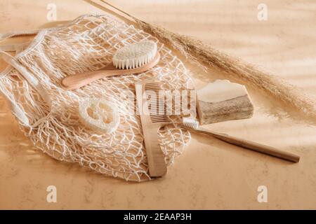 Zéro déchet accessoires de salle de bain brosse à cheveux, brosse à dents en bambou, loofah et savon naturel dans sac réutilisable sur fond beige. Vue de dessus. Vintage Banque D'Images