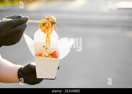 Gros plan les notes sur un arrière-plan flou sortent de la boîte blanche. Faites de la publicité pour la livraison au restaurant japonais. Restez à la maison et mangez des nouilles udon wi Banque D'Images