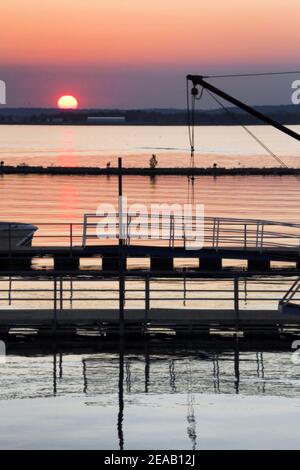 Vue sur Grand Lake depuis la rive, par le gréage de bateaux et la rampe de la marina tandis que le soleil se couche sous l'horizon à Grove Oklahoma. Banque D'Images
