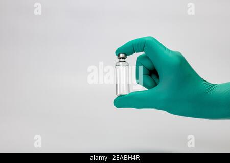 Main du médecin avec gant médical jetable tient le flacon de vaccin en main, détail, photo de symbole, coronavirus, vaccination, Banque D'Images