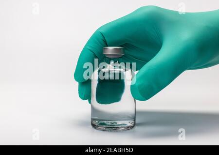 Main du médecin avec gant médical jetable tient le flacon de vaccin en main, détail, photo de symbole, coronavirus, vaccination, Banque D'Images