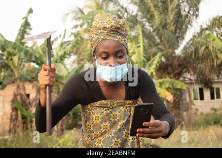 femme africaine utilisant son téléphone dans son jardin Banque D'Images