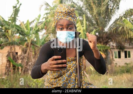 femme africaine utilisant son téléphone dans la ferme, femme africaine a mis un masque Banque D'Images