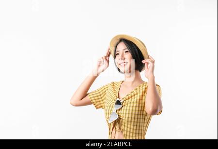 Photo studio de belle femme asiatique gaie dans une robe jaune et portant un chapeau et un stand sur fond blanc. Banque D'Images