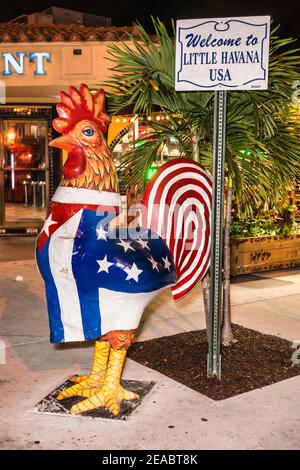 Statue de coq peinte avec des couleurs de drapeau américain et cubain à côté du panneau de bienvenue à la Little Havana de Miami. Banque D'Images