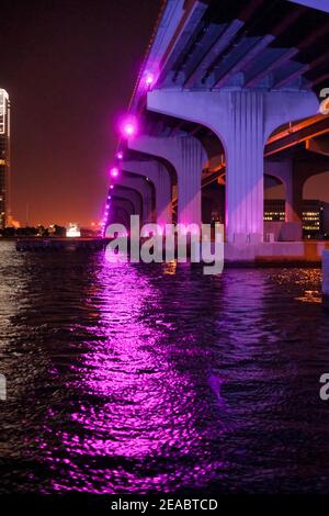 La sous-structure du pont MacArthur Causeway s'illumine la nuit avec des lumières magenta aux couleurs vives. Banque D'Images