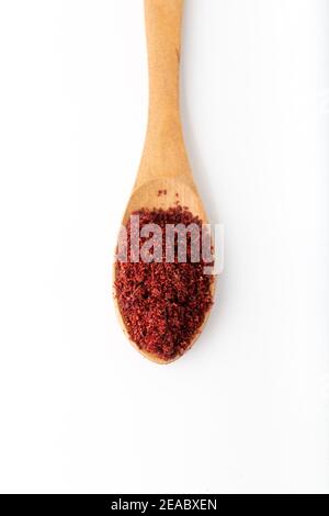 Flocons de poivron rouge séchés dans la cuillère en bois sur fond blanc. Banque D'Images