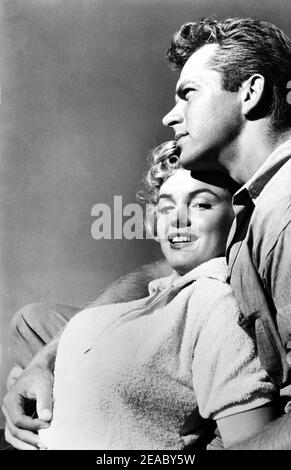 1951 , Etats-Unis : l'actrice MARILYN MONROE ( 1926 - 1962 ) et KEITH ANDES dans une pubblicity RKO encore pour le CLASH du film PAR NIGTH ( la confessione della signora Doyle ) Par Fritz Lang - FILM - CINÉMA - FILM - abbriscio - étreinte - amanti - amore - amour - innamorati - amants - sourire - sorriso - jeans camicia - chemise --- Archivio GBB Banque D'Images