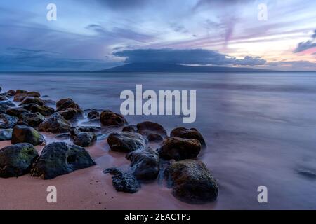 Rocky Shore - UNE vue à long terme d'un crépuscule coloré sur une plage rocheuse de la côte nord-ouest de l'île de Maui, Hawaii, États-Unis. Banque D'Images