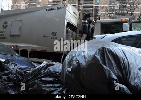 New York, États-Unis. 08 février 2021. Un camion du département de l'assainissement est stationné devant les ordures non collectées dans le bas de Manhattan, après deux tempêtes de neige qui ont frappé New York en une semaine, le 8 février 2021. Le département de l'assainissement de New York reprend la collecte des déchets après avoir chargé ses employés et ses camions de déneiger dans les cinq quartiers de New York. (Photo par Anthony Behar/Sipa USA) crédit: SIPA USA/Alay Live News Banque D'Images