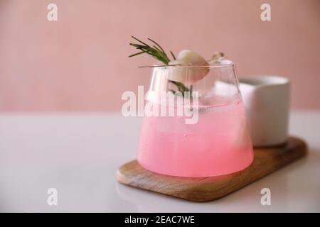 Cocktail rose au romarin et au lychee sur fond rose Banque D'Images