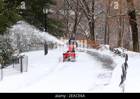 Un travailleur déneigement d'un sentier de Central Park à l'aide d'un souffleur après une tempête de neige hivernale à New York, New York. Banque D'Images