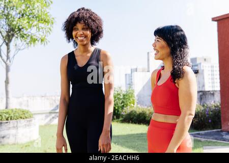 Adulte deux amis multiethniques portant des vêtements de sport marchant dans la conversation dans le parc extérieur. Les femmes africaines américaines et asiatiques parlent - concept d'amitié diverse Banque D'Images