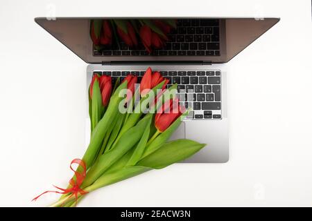 Les tulipes rouges se trouvent sur un ordinateur portable pour l’internationale des femmes Jour Banque D'Images