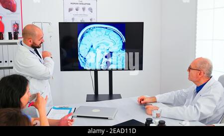 Médecins discutant avec des médecins spécialistes lors d'une conférence médicale. Médecin expert utilisant la technologie moderne, pointant sur la radiographie numérique brainstorming avec le personnel de médecine pour l'expertise. Banque D'Images