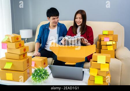 Couple d'entrepreneurs en ligne vérifiant et emballer une boîte à colis au bureau à domicile, préparer le produit pour la livraison au client, (PME) Banque D'Images