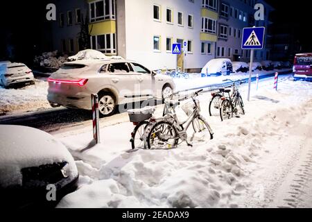 Hanovre, Allemagne. 09e février 2021. Une voiture traverse lentement une rue enneigée dans le sud de la ville tôt le matin. Credit: Hauke-Christian Dittrich/dpa/Alay Live News Banque D'Images
