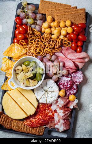 Assiette de charcuterie et fromage. Plateau de hors-d'œuvre avec assortiment de viandes, fromages, fruits, olives et crackers. Banque D'Images