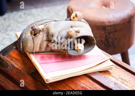 Souris en gros plan et chaussures brunes sur poitrine en bois. Souris dormant dans une vieille chaussure marron déchirée. Figurines dans le marché de rue Banque D'Images