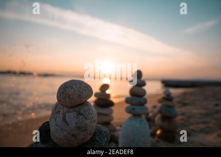 Des rochers se sont accumulés sur la plage et de l'eau les éclabousse au coucher du soleil de rêve Banque D'Images