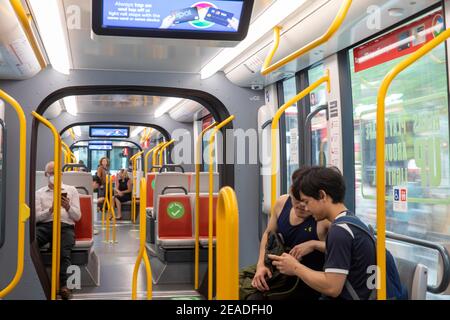 Sydney train léger carriole intérieur, les passagers se déplaçant, s'asseoir ici les autocollants agissent comme un social distancement pendant la pandémie Covid 19, Sydney, Australie Banque D'Images