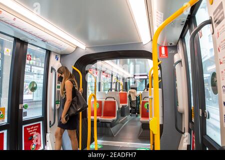 Femme sur le train léger de Sydney portant un masque Portes de sortie, rail léger de Sydney, Nouvelle-Galles du Sud, Australie pendant la pandémie du coronavirus Banque D'Images