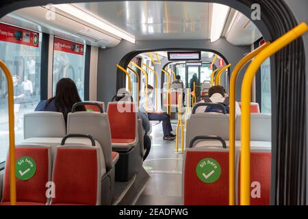 Sydney train léger carriole intérieur, les passagers se déplaçant, s'asseoir ici les autocollants agissent comme un social distancement pendant la pandémie Covid 19, Sydney, Australie Banque D'Images